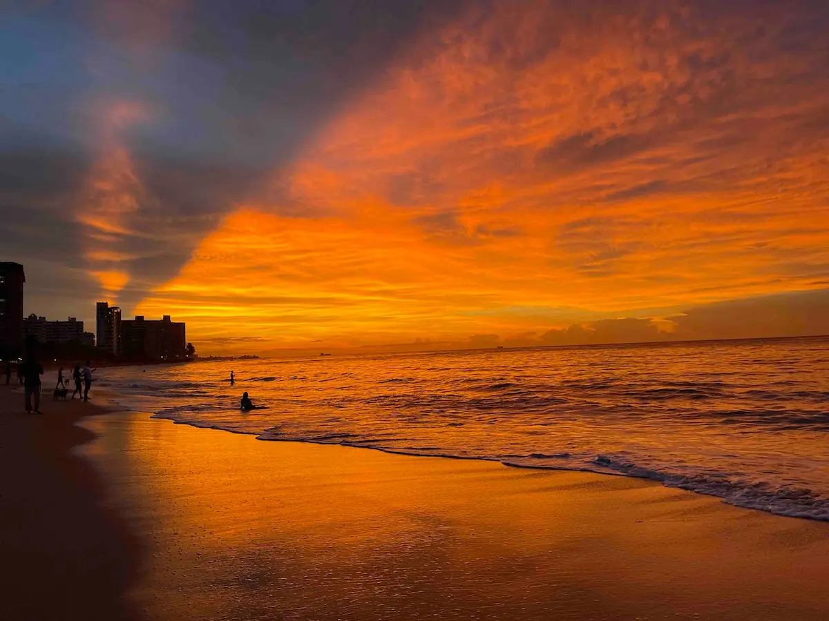 Sunset over the ocean at Ocean Park Beach, with people walking along the waterline.